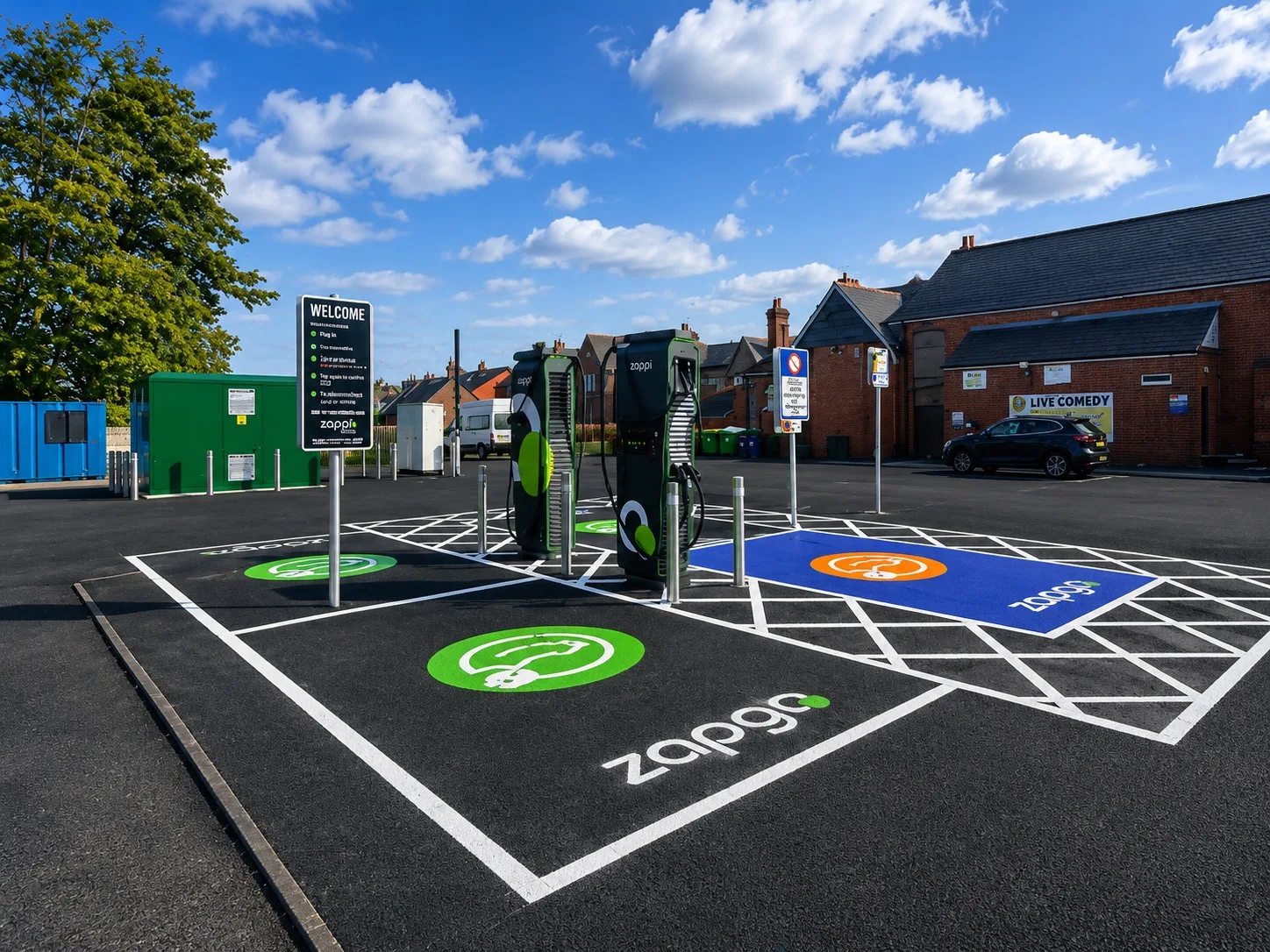 Two rapid charging units on a newly surfaced car park, serving green-marked charging bays and a blue accessible bay, with a ground-mounted electrical equipment cabinet behind